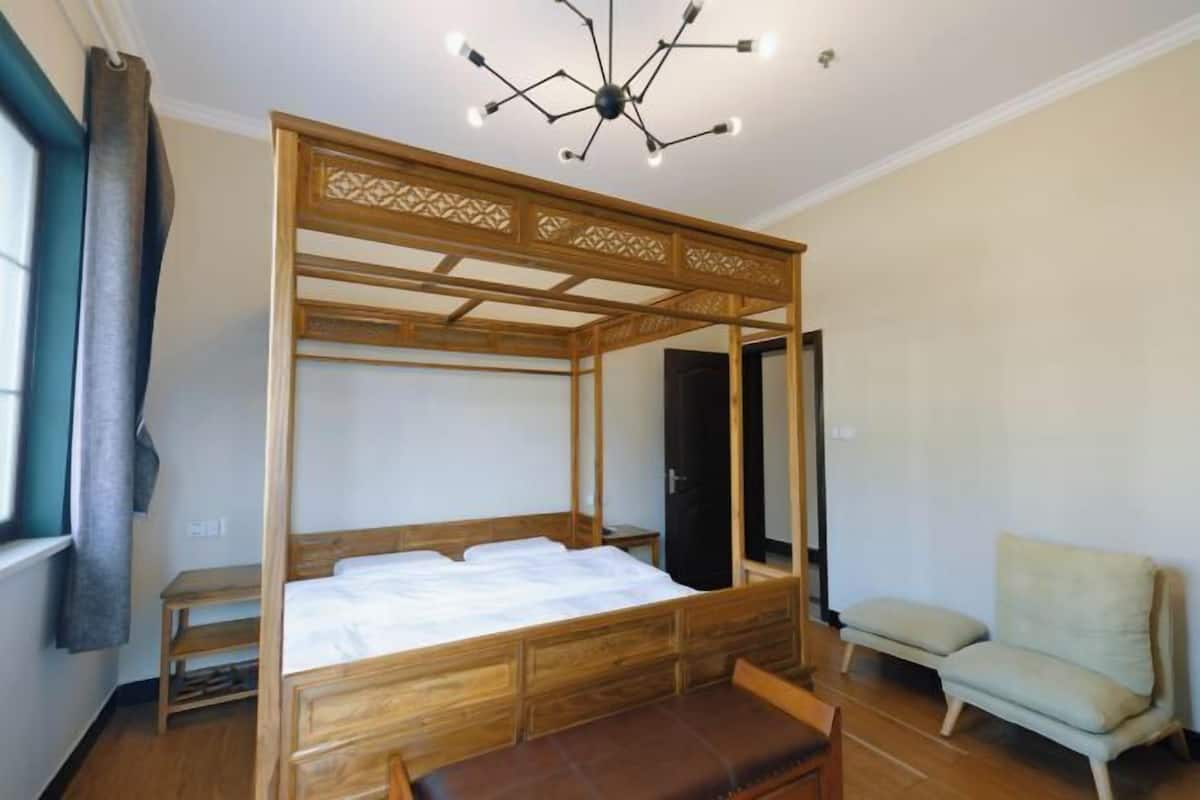 A room with a four-poster bed, a bench, a chair, and a mirror.