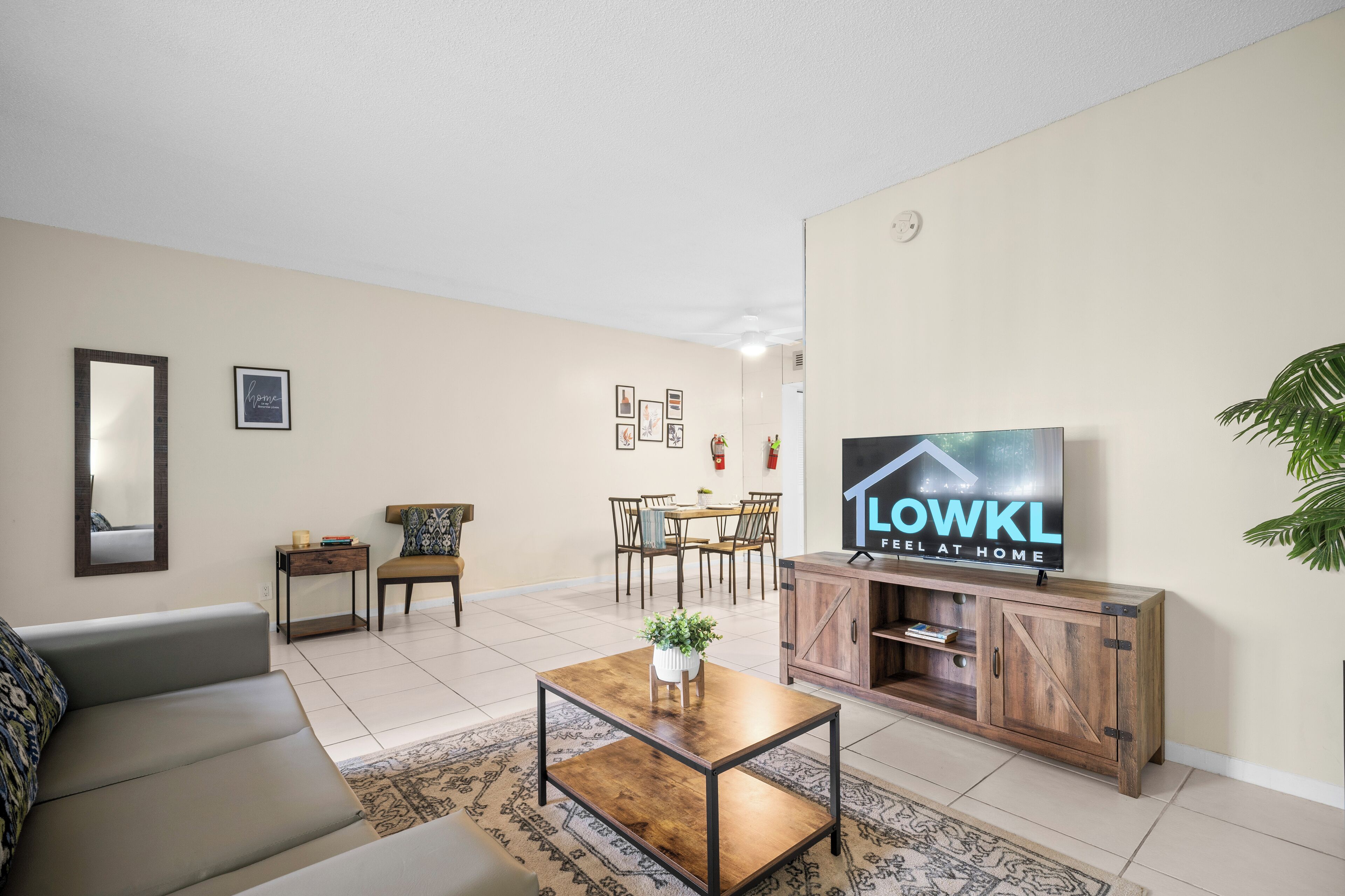 Een woonkamer met een bank, salontafel, televisie en een eethoek met stoelen en een tafel.