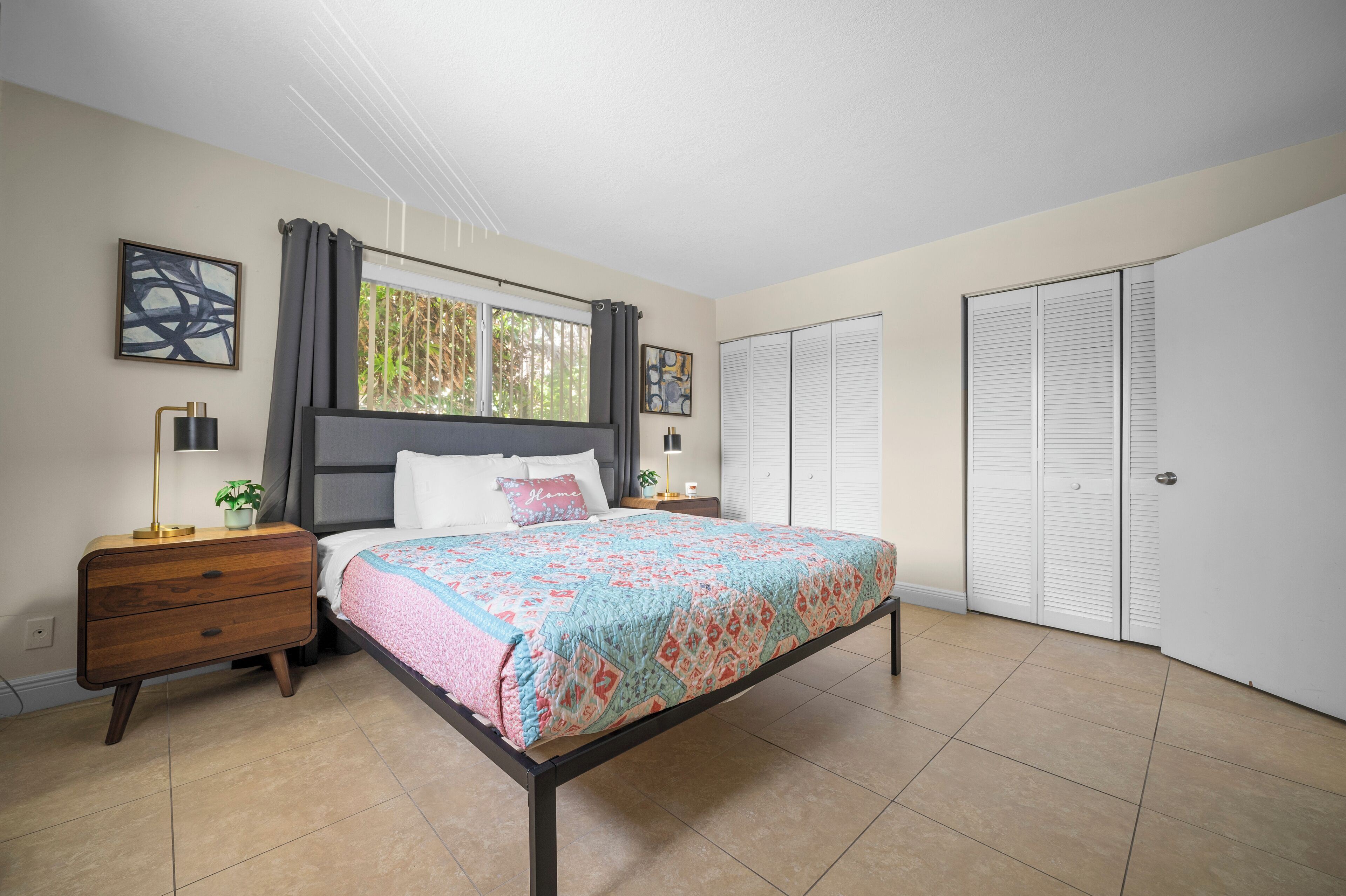 A bedroom with a bed, nightstand, lamp, and a window with curtains.
