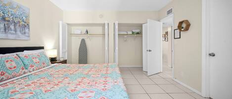 A bedroom with a bed, a wardrobe, and a hallway leading to another room.