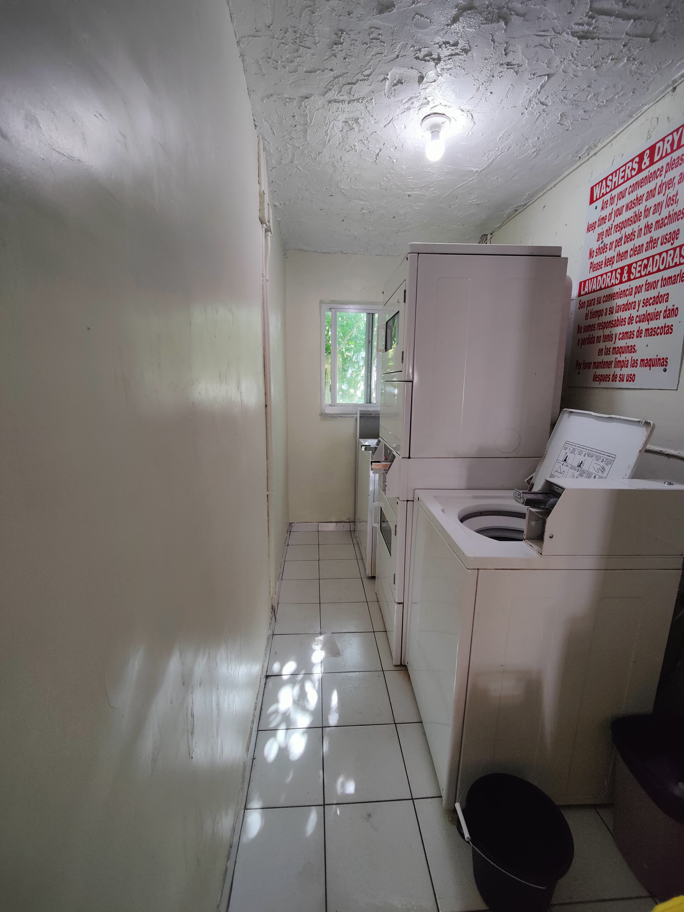 Un bagno stretto, con piastrelle, dotato di toilette, lavandino e un armadietto bianco. Un cartello in spagnolo fornisce istruzioni per l'uso dei servizi igienici.