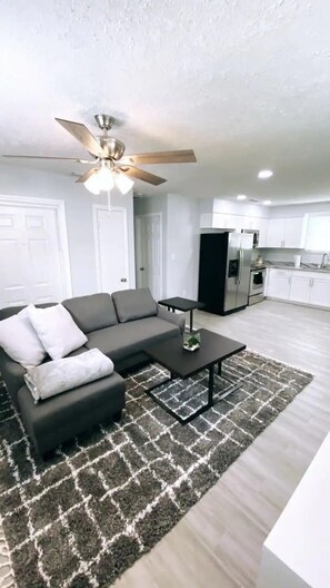 A modern living room with a sectional sofa, a coffee table, and a patterned rug. - Remodeled modern home (Port Richey)