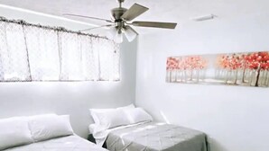 A bedroom with two beds, a ceiling fan, and a painting on the wall. - Remodeled modern home (Port Richey)