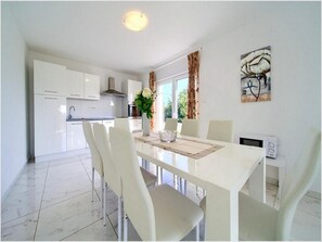 Enjoy meals in this stylish dining area with a white table, chairs, and a microwave.