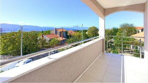 Un balcón con vista a una zona residencial, con casas y montañas a lo lejos.