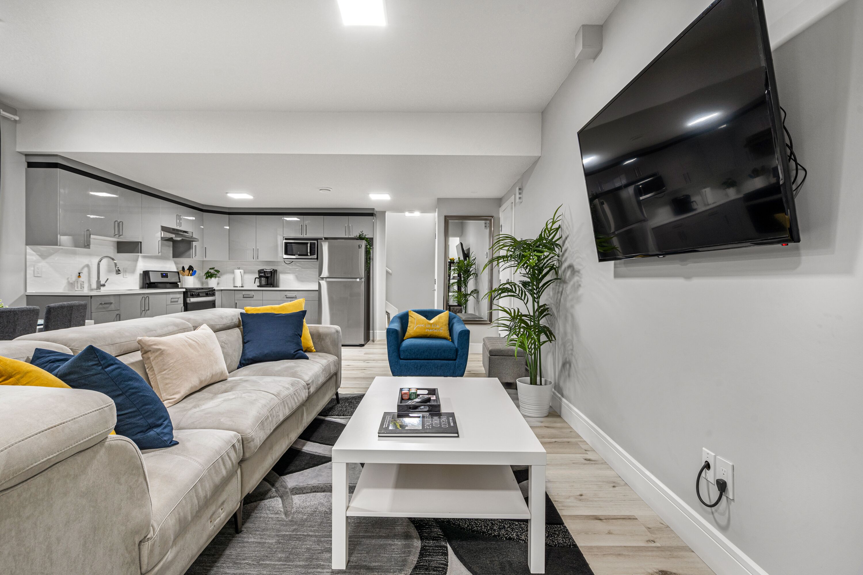 Een moderne woonkamer met een bank, salontafel en een aan de muur bevestigde televisie.