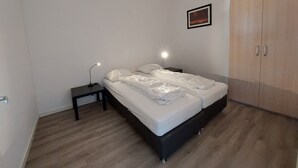 Een slaapkamer met een bed, nachtkastjes, een kledingkast en een ingelijste foto aan de muur.