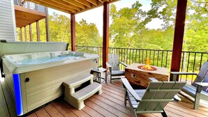 Uma banheira de hidromassagem em um deck de madeira, com móveis de exterior e vista para árvores.