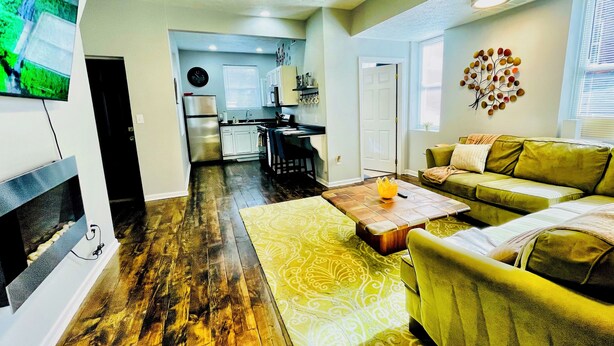 A living room with a green sofa, a patterned rug, and a coffee table. - Walk to ACRISURE in 23 Mins!  King Bed + FREE private park ✭Perfect Locale✭ (Pittsburgh)