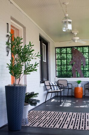 A covered porch with a large potted plant, outdoor seating, and a decorative lantern. - Downtown Marion 5BR Sleeps 10 Bigfoot Bungalow Pet Friendly Easy Roads Mountains (Marion)