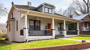 A single-story house with a porch, a chimney, and a brick foundation.