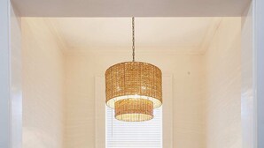 A cozy nook with a white bench, a small table with a bowl, and a woven pendant light.