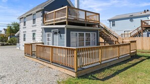 A two-story house with a wooden deck and a staircase leading to the upper level. - Fishermen's Catch (Frederica)