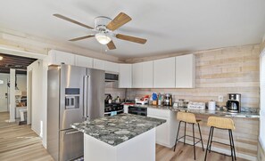 Una cocina moderna con una isla central, electrodomésticos de acero inoxidable y un ventilador de techo.