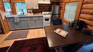 Una cucina compatta con pareti in legno, un fornello, un frigorifero e un tavolo da pranzo con un sottotavolo.