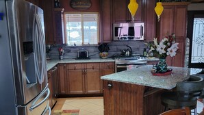 Eine Küche mit Holzausstattung, einem Edelstahlkühlschrank, einer Mikrowelle und einer Arbeitsplatte aus Granit.