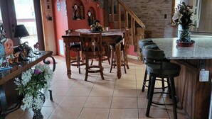 Ein Essbereich mit Holztisch und -stühlen, eine Küchenzeile mit Blumen in einer Vase und eine Treppe, die in eine weitere Ebene führt.