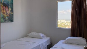 A hotel room with two single beds, a window with curtains, a ceiling light, and a painting on the wall. - 3TP-27 APARTAMENTO DE 3 HABITACIONES (Cartagena)