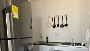 A modern kitchen with a stainless steel refrigerator, white cabinets, a built-in oven, and a hanging pot rack. - 3TP-27 APARTAMENTO DE 3 HABITACIONES (Cartagena)