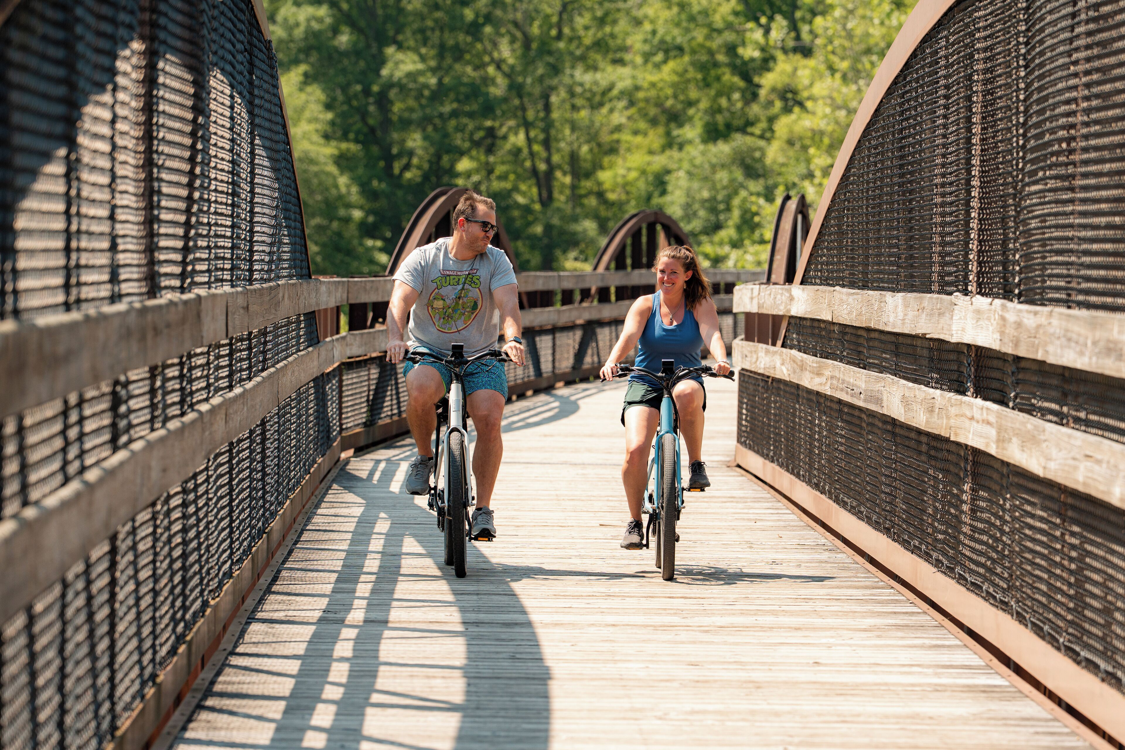 A wooden pedestrian bridge with metal railings and a wooden walkway.