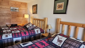 A cozy room with two beds, wooden headboards, and a quilted bedspread featuring animal prints.
