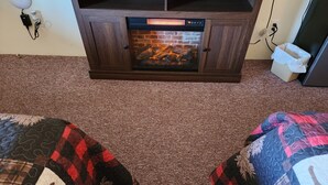 Una habitación con chimenea, piso alfombrado y dos camas con ropa de cama estampada.