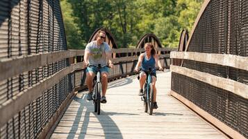 Two people riding bicycles on a wooden bridge with metal railings.
