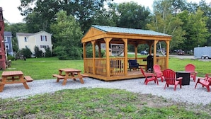 A wooden gazebo with a roof, surrounded by picnic tables and red chairs. - Family Suite in Ohiopyle- Walk to Falls & Trails (Ohiopyle)