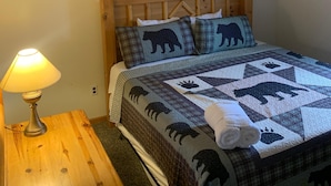 A bedroom with a wooden headboard, a quilted bedspread with animal prints, a bedside lamp, and a framed picture on the wall. - Family Suite in Ohiopyle- Walk to Falls & Trails (Ohiopyle)