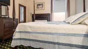 A bedroom with a four-poster bed, a dresser, a painting on the wall, and a window with curtains. - The Monroe | Historic Victorian Inn Room (Farmington)