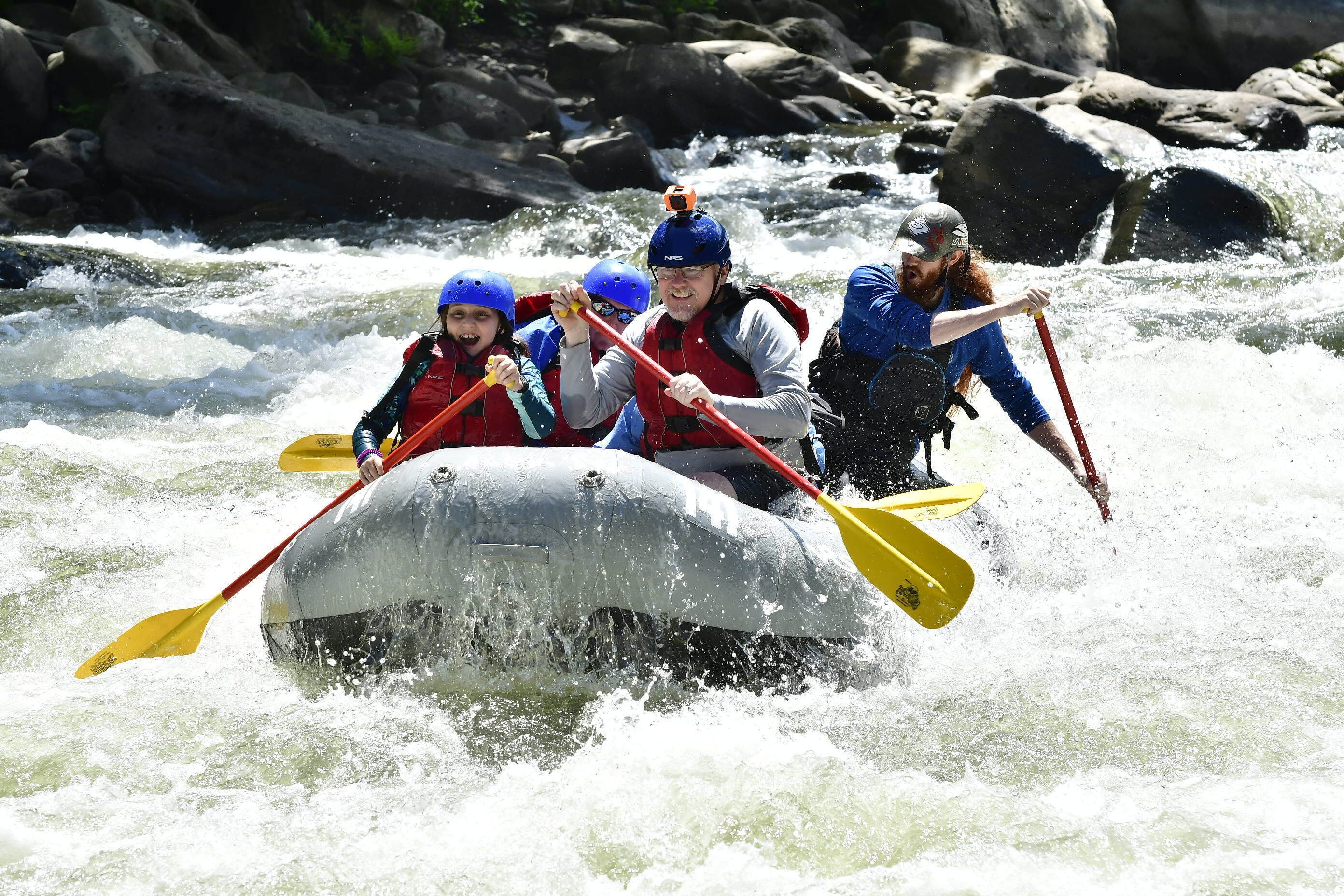 Un grupo de personas en balsas navegando un río con rápidos.