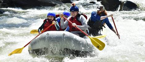 Un grupo de personas en balsas navegando un río con rápidos.