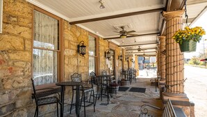 A covered outdoor seating area with stone walls, metal furniture, and hanging flower baskets. - The Jumonville | Jacuzzi Tub Historic Inn Room (Farmington)