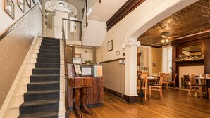A staircase leading to a second floor, wooden flooring, a reception desk, and a dining area with chairs and tables. - The Jumonville | Jacuzzi Tub Historic Inn Room (Farmington)
