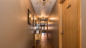 A hotel hallway with wooden floors, a wooden door labeled "6", and a coffee machine on a small table. - JV Thompson | Jacuzzi Tub Historic Inn Room (Farmington)