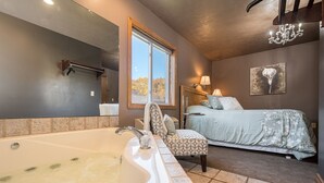 Ein Badezimmer mit einer großen Badewanne, einer Dusche und einem Fenster mit Blick auf Bäume.
