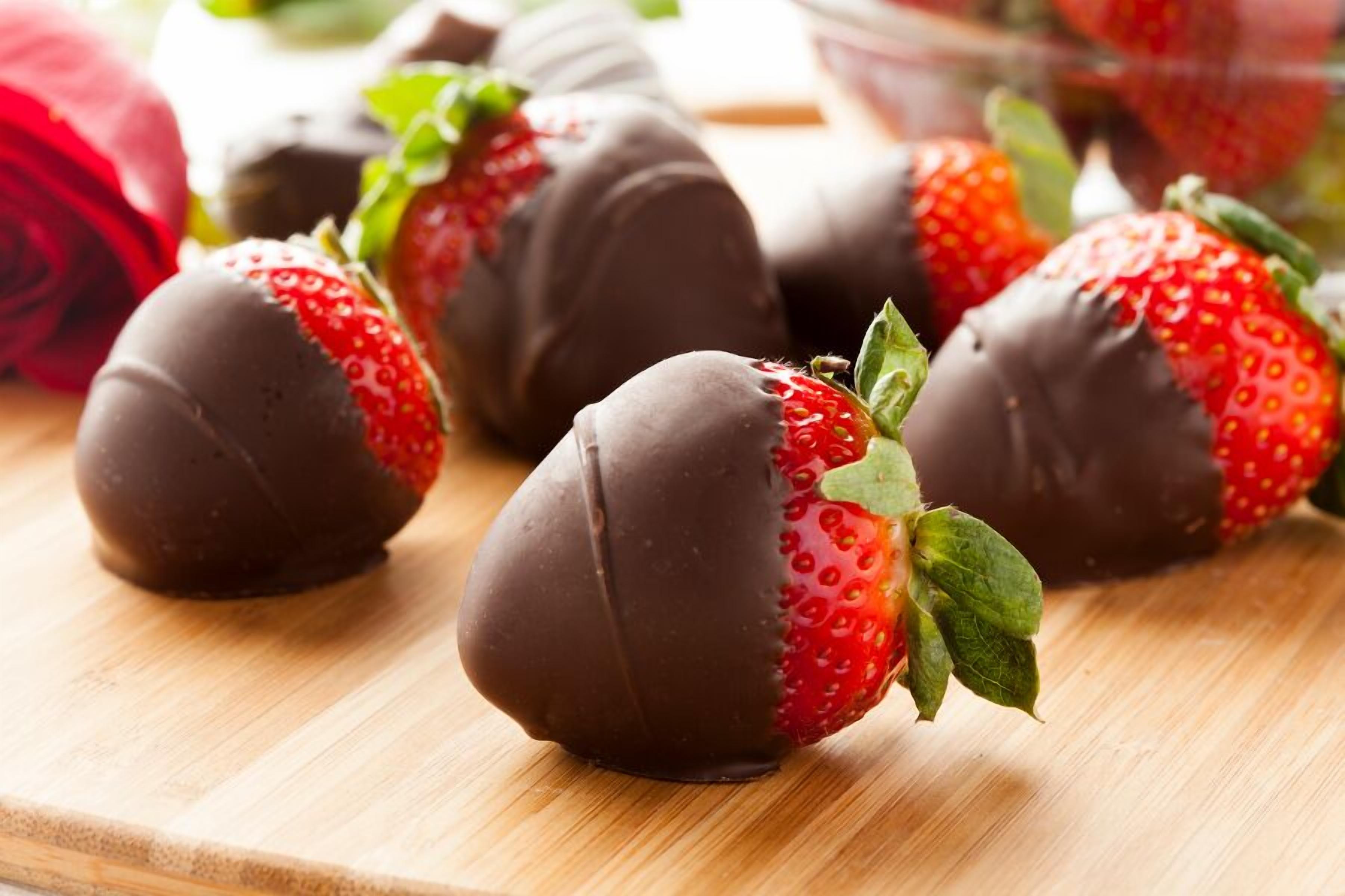 Fresas bañadas en chocolate sobre una superficie de madera.