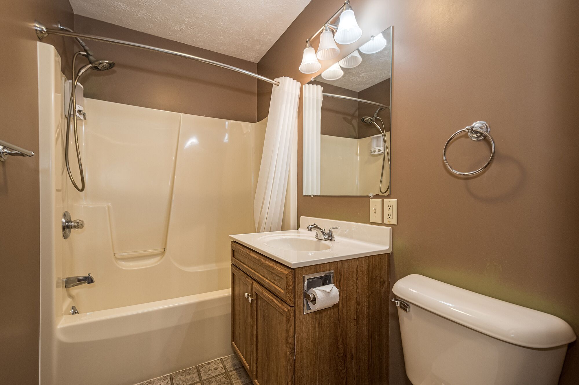 A bathroom with a bathtub, a sink, a toilet, and a mirror.