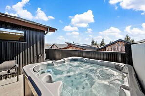 A hot tub with a wooden deck and a view of houses in the background.