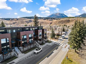 A modern multi-story building with a parking lot and a road in the foreground.