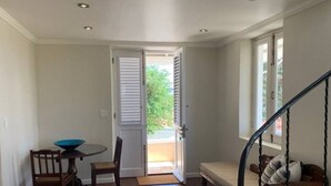Ein Zimmer mit Esstisch und Stühlen, einer Bank, einer Treppe und einer Tür zu einem Außenbereich.