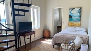Ein Schlafzimmer mit einem Bett, einem Sessel, einem Schreibtisch, einem Fernseher und einer Wendeltreppe.