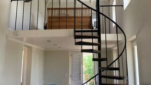 Ein geräumiger Loft mit Wendeltreppe, Essbereich und hoher Decke mit Ventilator.