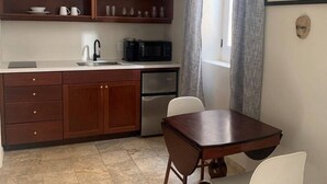 Una cocina compacta con armarios de madera, un lavamanos, una cafetera y una mesa de comedor con sillas.