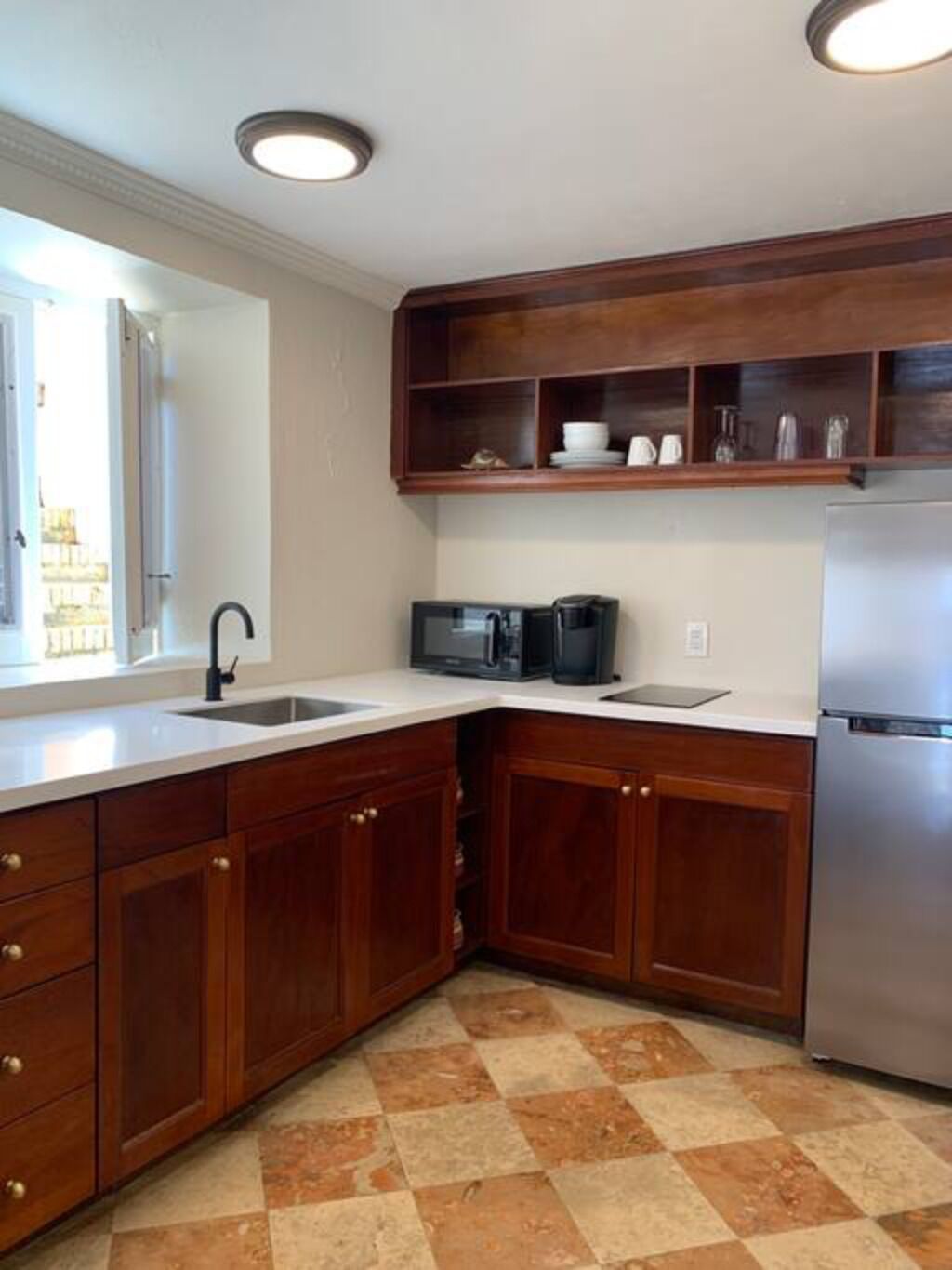 A kitchen with wooden cabinets, a stainless steel refrigerator, a microwave, and a coffee maker.