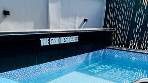 A swimming pool with a tiled edge and metal handrails. - THE GRID RESIDENCE (Lagos)