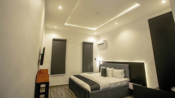A modern bedroom with a bed, bedside table, and a ceiling light fixture. - THE GRID RESIDENCE (Lagos)