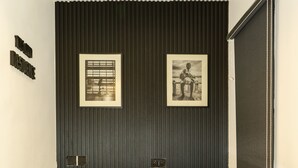 A modern room with a dark wooden panel wall, a white counter, and two framed pictures. - THE GRID RESIDENCE (Lagos)