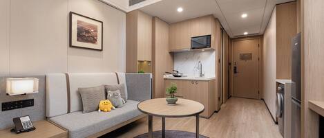 A compact living space with a sofa, a small table, a microwave, and a refrigerator.