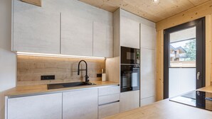 Una cucina moderna con mobili chiari in legno, un lavello in acciaio inossidabile e un forno.